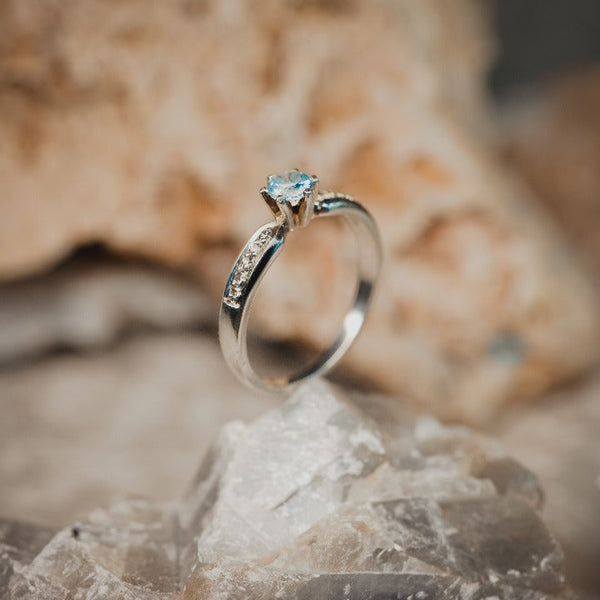 Anillo de compromiso con topacio natural y cristales laterales realizado en oro blanco de 14 kilates