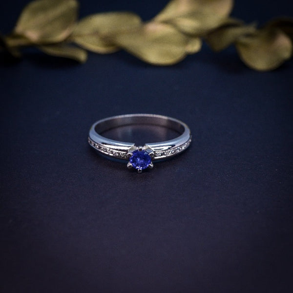 Anillo de compromiso con zafiro natural de .20ct y 10 diamantes laterales realizado en oro blanco de 14 kilates