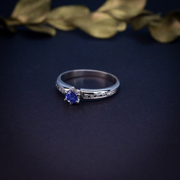 Anillo de compromiso con zafiro natural y cristales laterales realizado en oro de 14 kilates