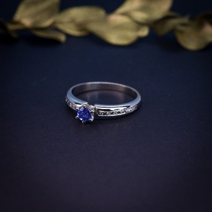 Anillo de compromiso con zafiro natural de .20ct y 10 diamantes laterales realizado en oro blanco de 14 kilates