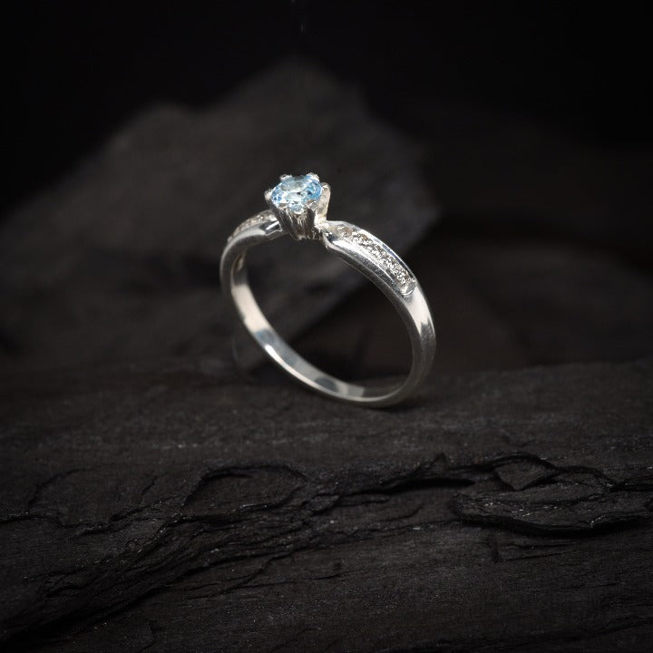 Anillo de compromiso con topacio natural y cristales laterales realizado en oro blanco de 14 kilates