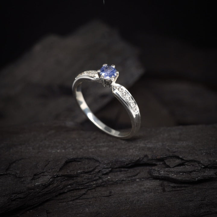 Anillo de compromiso con tanzanita natural y cristales laterales realizado en oro blanco de 14 kilates