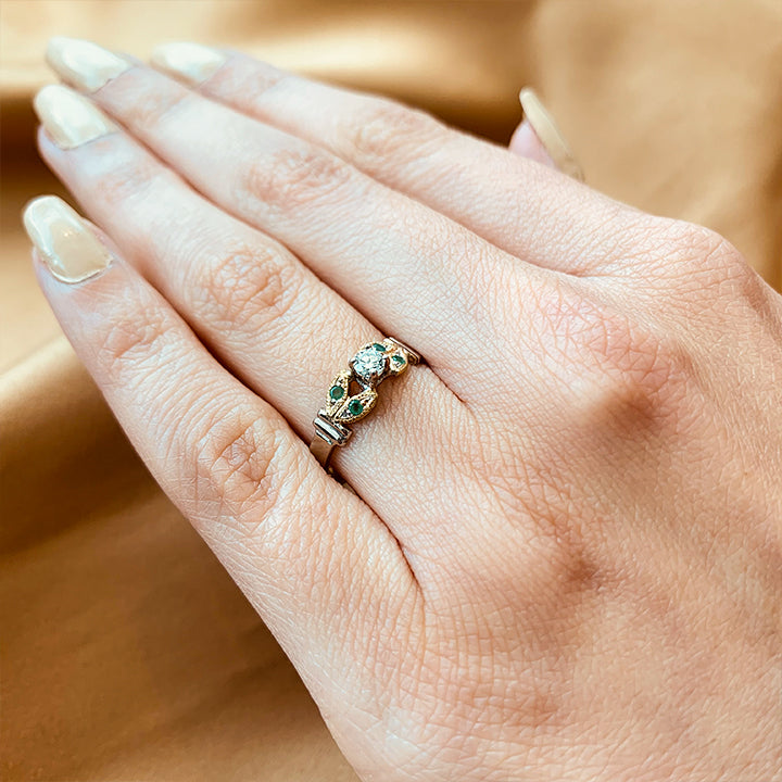 Anillo de compromiso con diamante natural de .15ct y esmeraldas laterales elaborado en oro amarillo y blanco de 14 kilates