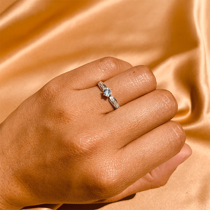 Anillo de compromiso con topacio natural y cristales laterales realizado en oro blanco de 14 kilates