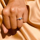 Anillo de compromiso con topacio natural y cristales laterales realizado en oro blanco de 14 kilates