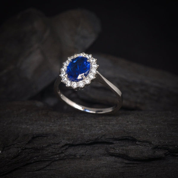 Anillo de compromiso con cristal azul y cristales laterales elaborado en oro blanco de 14 kilates