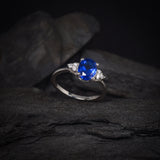 Anillo de compromiso con cristal azul y cristales laterales elaborado en oro blanco de 14 kilates