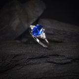 Anillo de compromiso con cristal azul y cristales laterales elaborado en oro blanco de 14 kilates